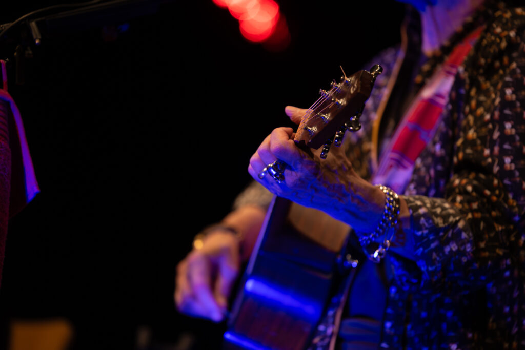 Detailaufnahme einer Gitarre spielenden Hand auf der Bühne