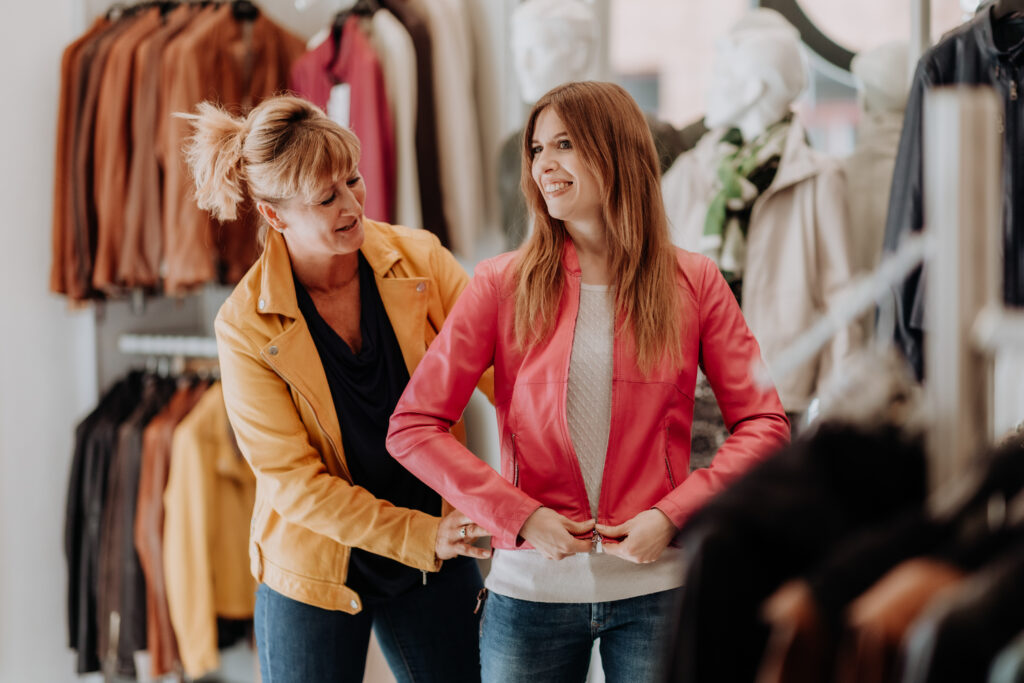 Zwei Frauen beim Anprobieren einer pinken Lederjacke im Geschäft Stoichart Leder in Graz.