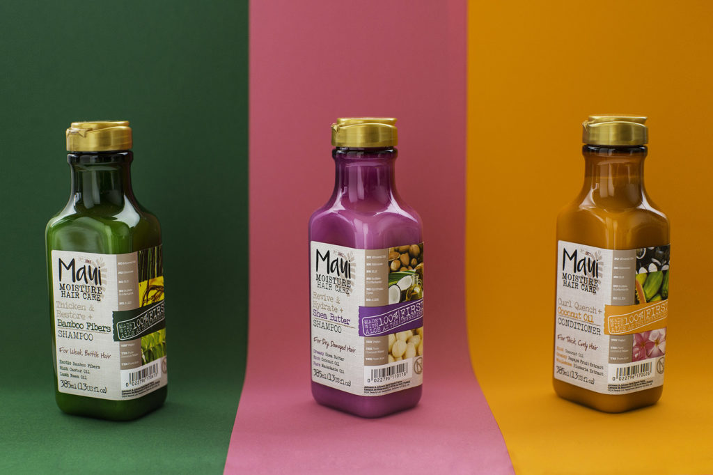 Drei Maui Moisture Haarpflegeprodukte – Shampoo und Conditioner – auf grün-pink-orangefarbenem Hintergrund nebeneinander aufgereiht