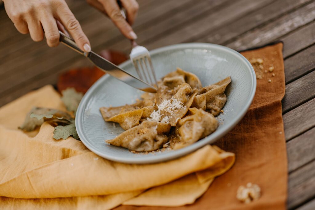 Kürbisravioli mit Walnussbutter und frisch geriebenem Parmesan, aufgeschnitten auf Teller – aufgenommen im Deli Leibnitz.