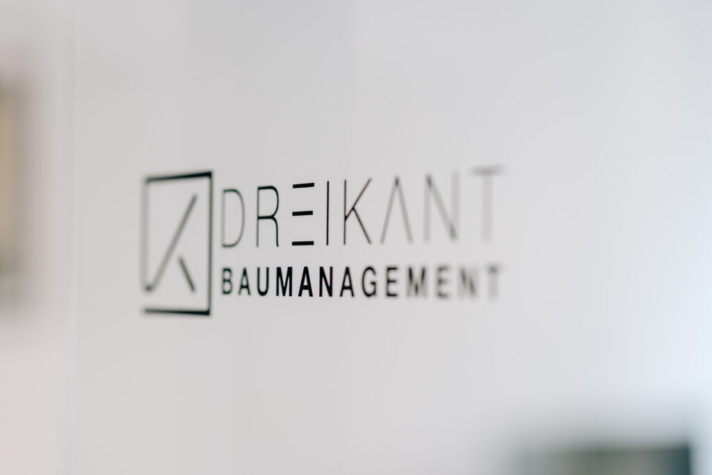 Nahaufnahme des Logos von Dreikant Baumanagement auf einer Glastür in Schwarz-Weiß-Optik.