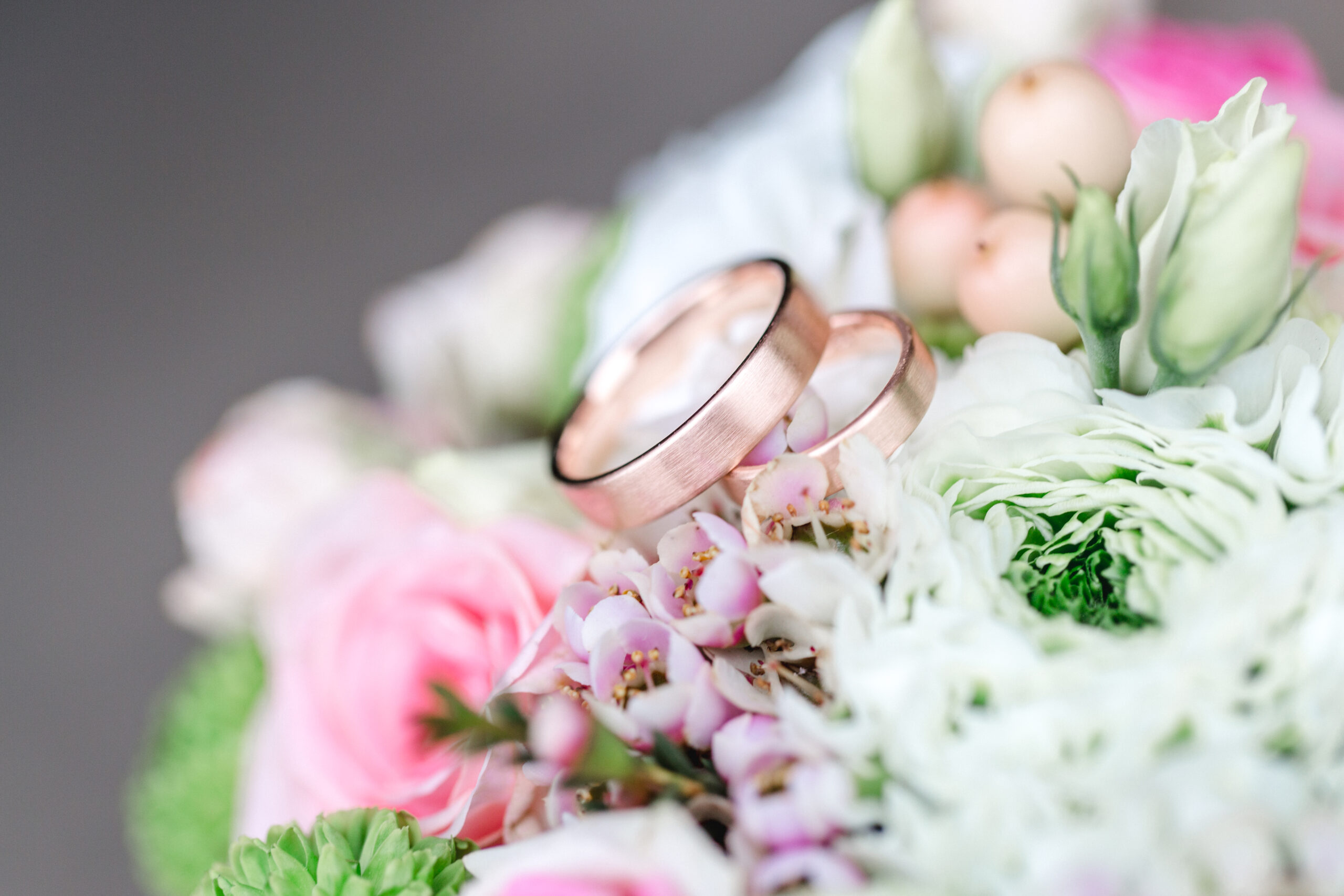 Makroaufnahme von Hochzeitsringen an rustikalem Dekoelement.