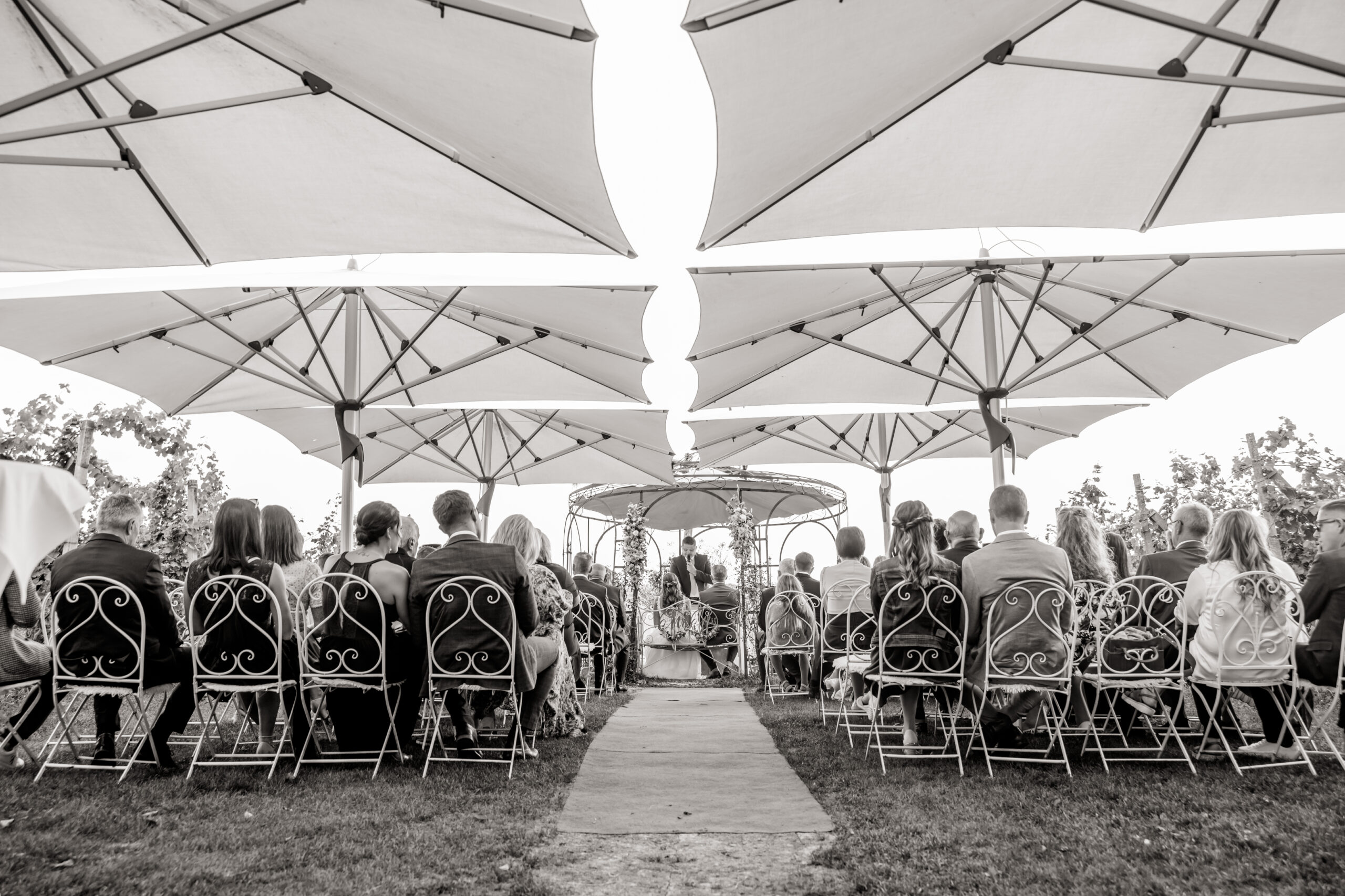 Gäste sitzen unter einem Zeltdach während der Trauung.